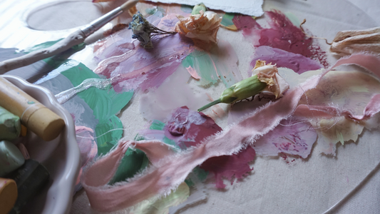 artist paint palette with dried paints splattered across. paint colors are green, pink and lavender