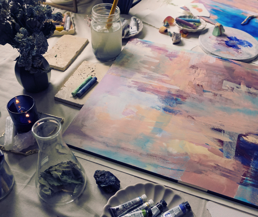 artist table with abstract painting and varioud art supplies