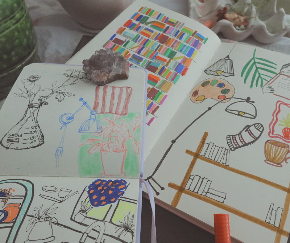 artist desk with open sketchbooks with sketches of books, plants and home decor items